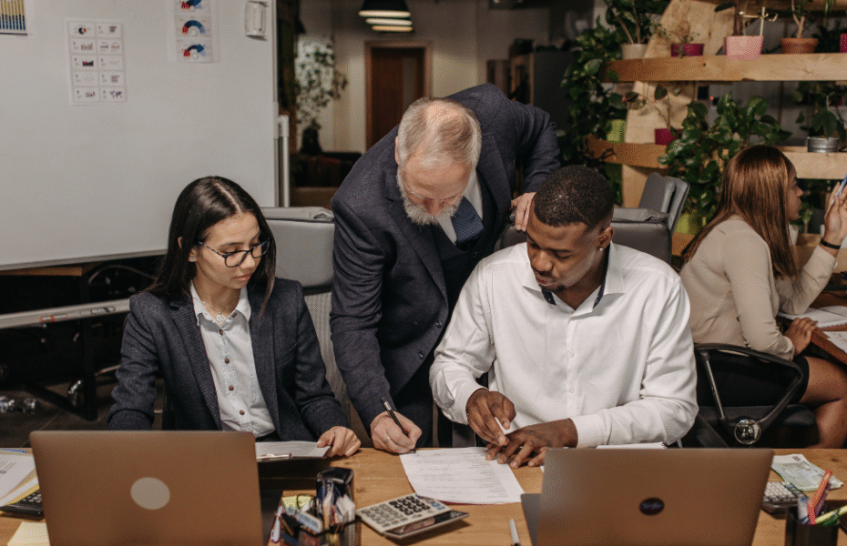 Scott Voltz collaborating with a diverse appraisal team in a modern office, discussing commercial real estate strategies and business growth.