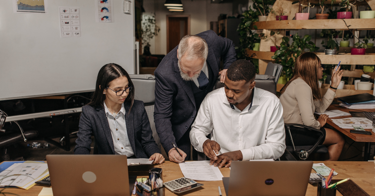 Scott Voltz collaborating with a diverse appraisal team in a modern office, discussing commercial real estate strategies and business growth.
