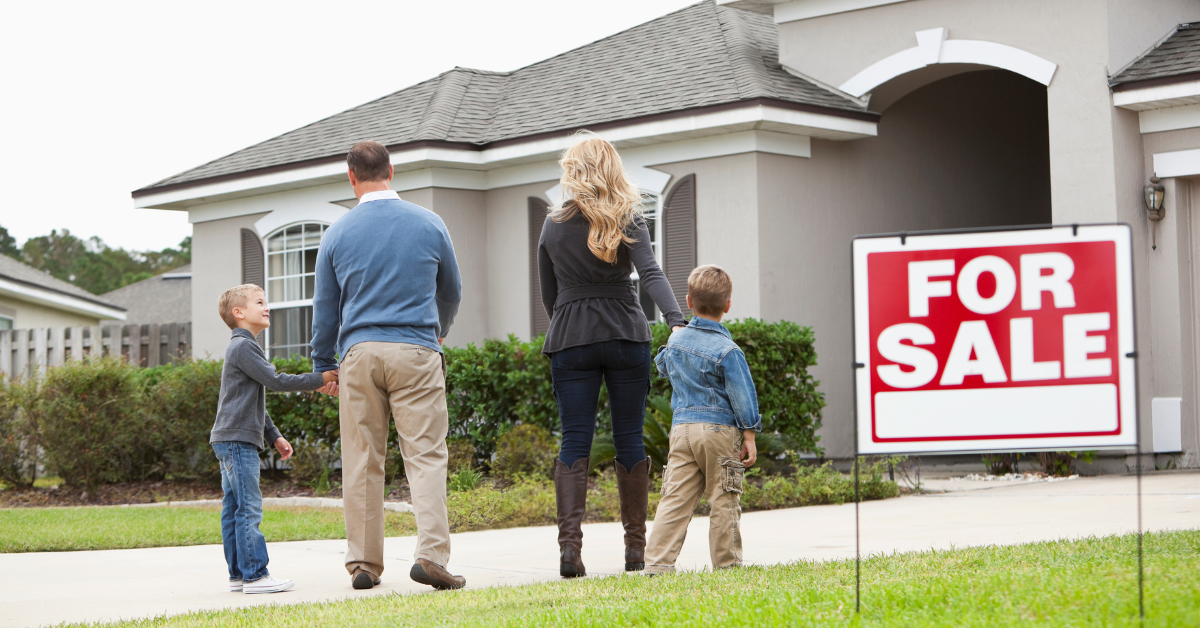 Family in Front of a House with “For Sale” Sign
